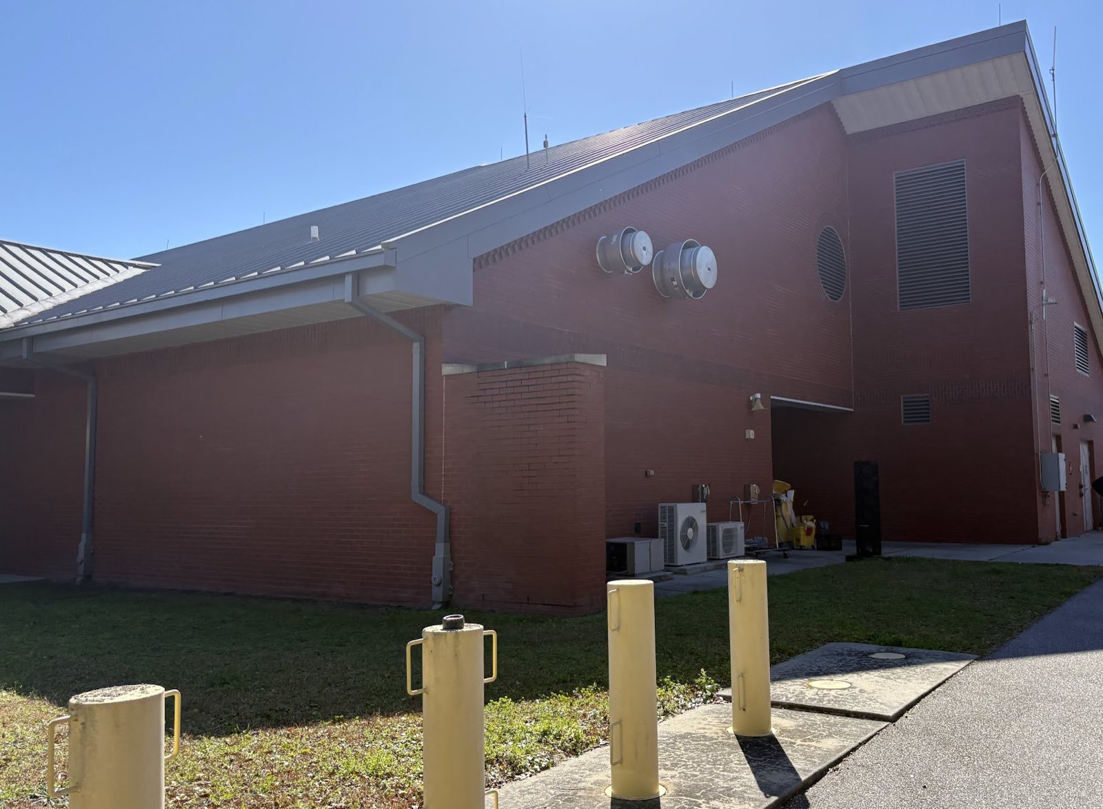 A row of yellow steel bollards along the walkway of a brick early childhood facility